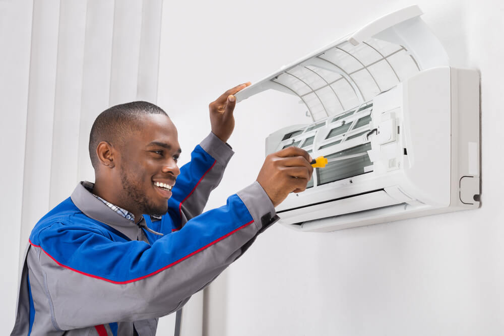 landlord-resources-blueground-ac-maintenance-male-technician-fixing-ac-unit-wearing-blue-and-grey-shirt